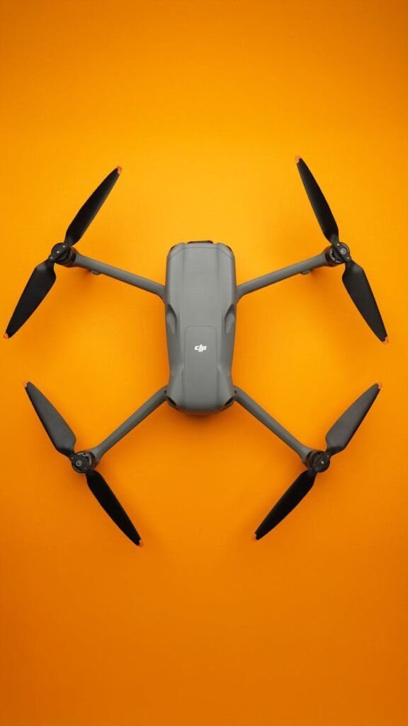 🚁 Best Beginner Drone Kits on Amazon (Drone + Extra Batteries) — 2026 Guide Top view of a sleek folding drone isolated on a vibrant orange background.