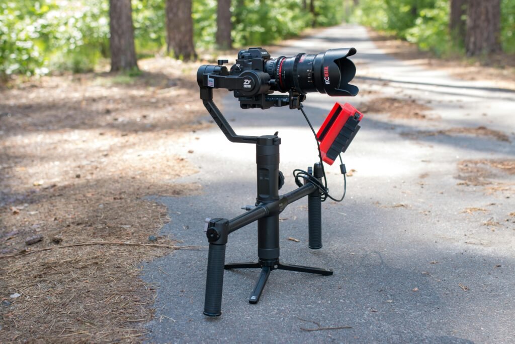 top tripods and stabilizers for vlogging from Amazon (2026) A professional camera on a gimbal setup in a peaceful forest pathway.